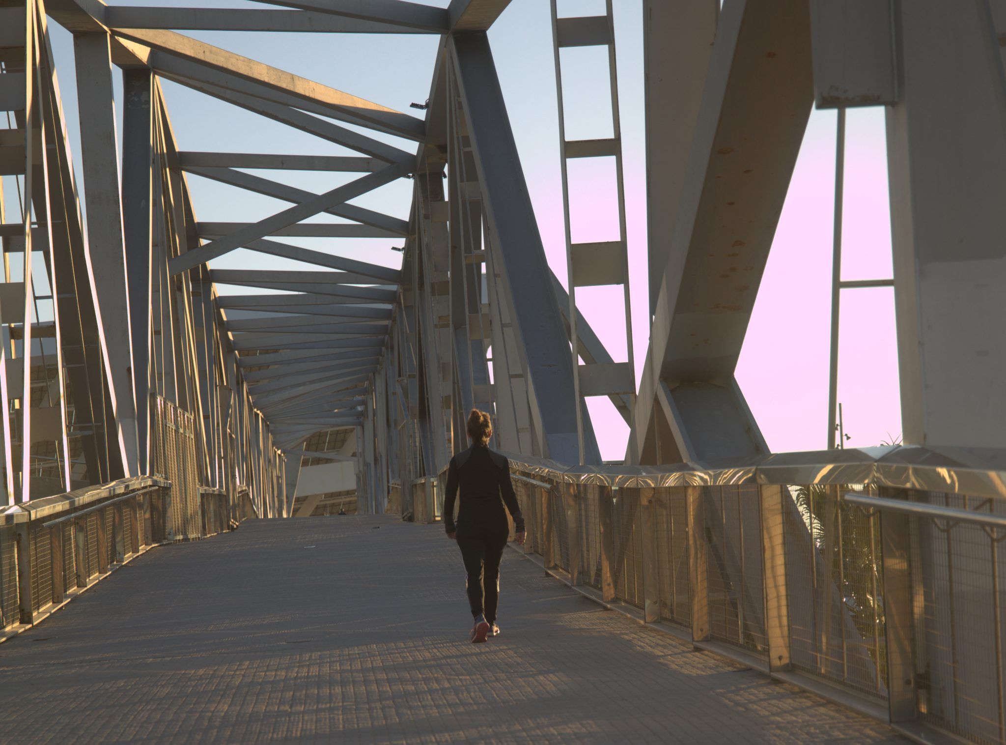 Persona caminando por un puente de acero.