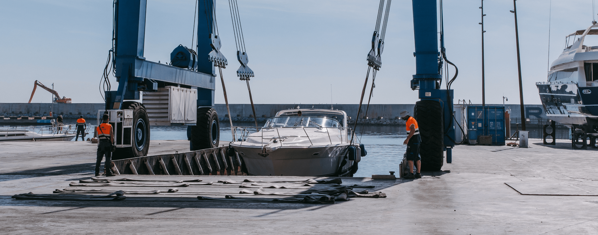 Barco en varadero con grúa y operarios.