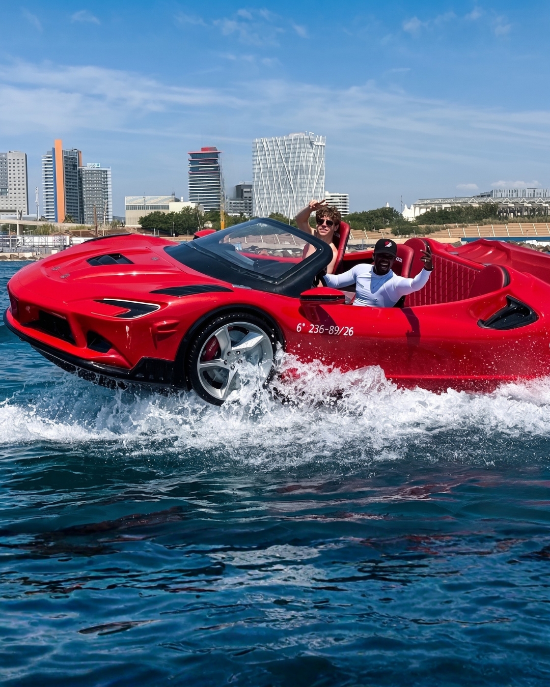 Pareja en coche deportivo rojo acuático en Port Fòrum