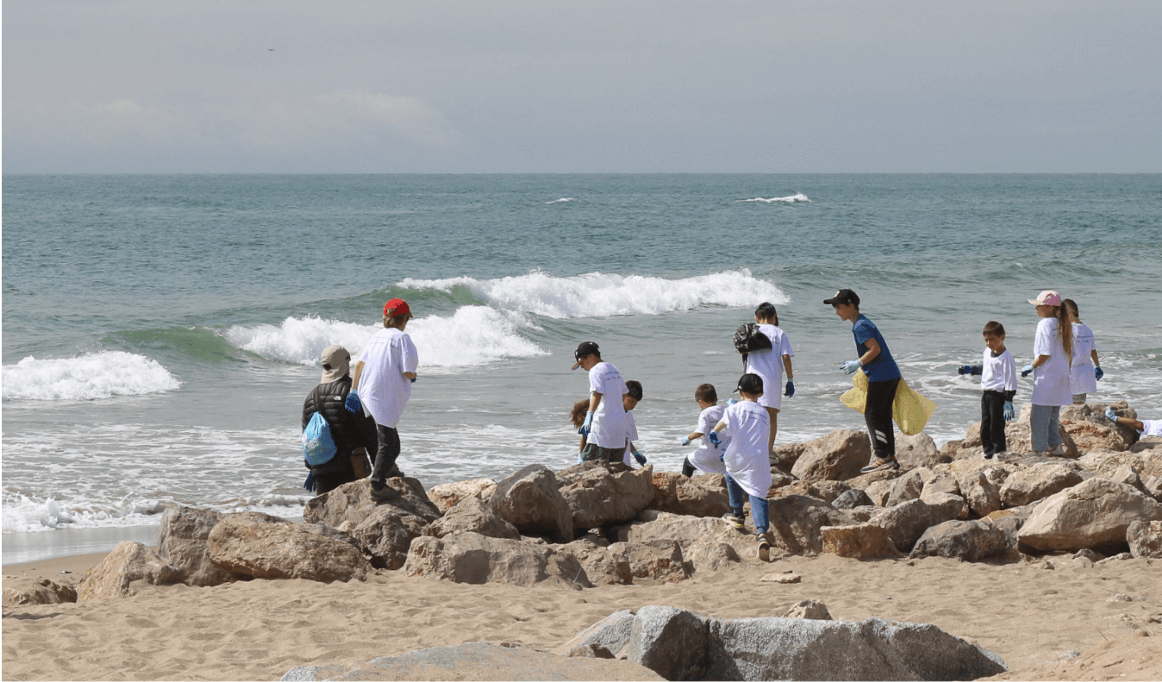 Niños limpian playa con olas